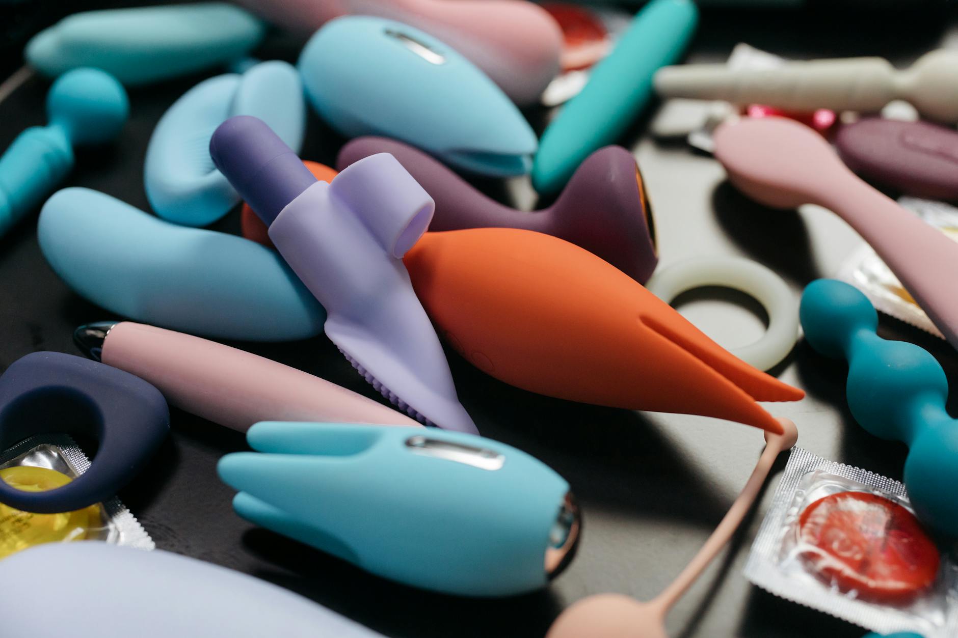 Close-up view of vibrant adult toys including clitoral vibrators and rings on a neutral background.