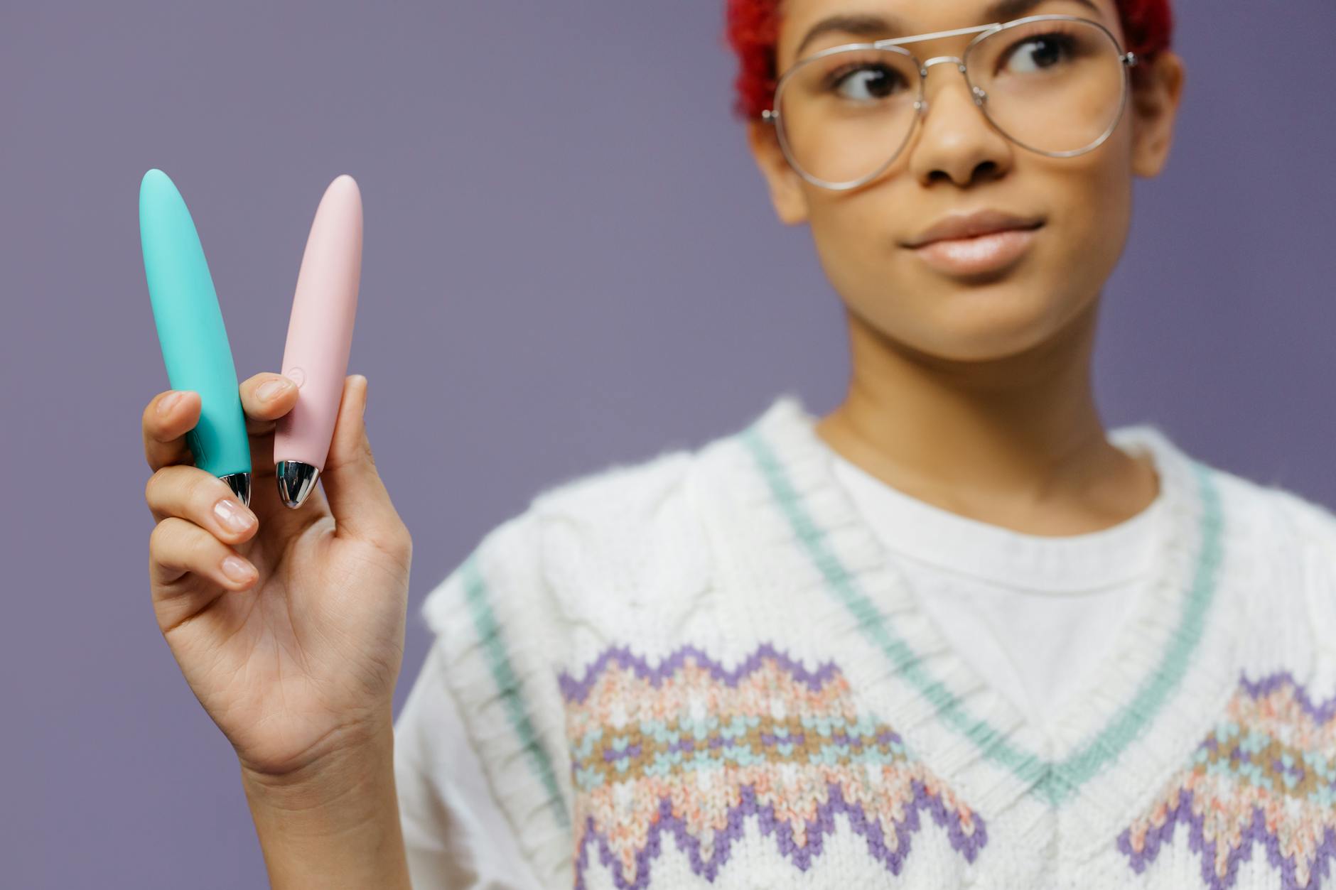 A woman holding vibrators against a purple background, illustrating age-inclusive pleasure